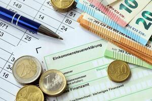 KYIV, UKRAINE - APRIL 20, 2024 Einkommensteuererklarung inscription from blank tax form and many euro banknotes on office table photo