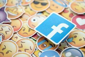 KYIV, UKRAINE - APRIL 20, 2024 Facebook logo and large set of stickers with Emoji yellow faces. Emoji is a pictogram or smiley embedded in text and used in electronic messages photo