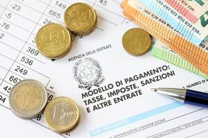 KYIV, UKRAINE - APRIL 20, 2024 Agenzia Delle Entrate logo from blank tax form and many euro banknotes on office table photo