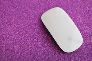 KYIV, UKRAINE - NOVEMBER 27, 2023 Apple Magic Mouse 3rd generation lies on sparkling glitter surface photo