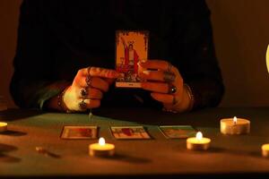 KYIV, UKRAINE - JULY 10, 2024 Tarot reader picking tarot cards. Candlelight in dark room. Tarot reader or fortune teller reading and forecasting photo
