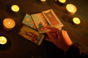 KYIV, UKRAINE - JULY 10, 2024 Tarot reader picking tarot cards. Candlelight in dark room. Tarot reader or fortune teller reading and forecasting photo