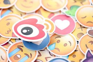 KYIV, UKRAINE - APRIL 20, 2024 Weibo logo and large set of stickers with Emoji yellow faces. Emoji is a pictogram or smiley embedded in text and used in electronic messages photo