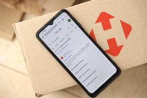 KYIV, UKRAINE - APRIL 20, 2024 Nova Poshta Logotype on cardboard box and website on smartphone screen. Nova Poshta is best ukrainian postal service company photo