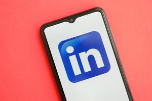 KYIV, UKRAINE - APRIL 1, 2024 LinkedIn icon on smartphone screen on red table photo