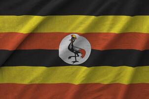 Uganda flag depicted on folded wavy fabric of old cloth photo