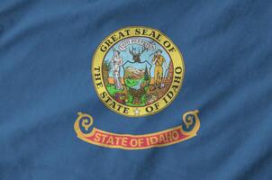 Idaho US state flag depicted on folded wavy fabric of old cloth photo