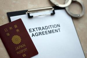 Passport of Japan and Extradition Agreement with handcuffs on table photo