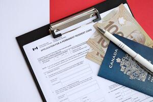 Application for permanent resident card on table with pen and canadian passport with money photo