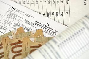 Canadian T4 tax form Statement of remuneration paid lies on table with canadian money bills photo