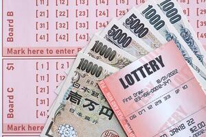 Lottery tickets lies with japanese yen bills on gambling sheets with numbers for marking to play lottery photo