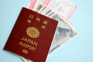 Japan passport with money and airline tickets on blue background close up photo