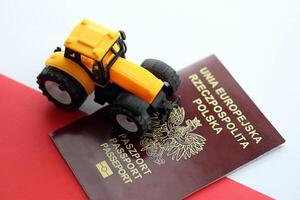 Red polish passport and yellow tractor on smooth red and white flag of Poland photo