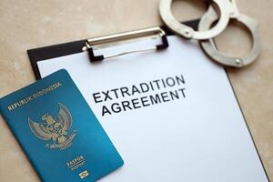 Passport of Indonesia and Extradition Agreement with handcuffs on table photo