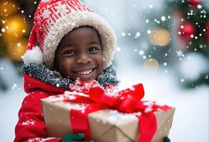 Joyful toddler with Christmas gift amidst snowflakes. Portrait of a kid on a winter street in close-up. photo