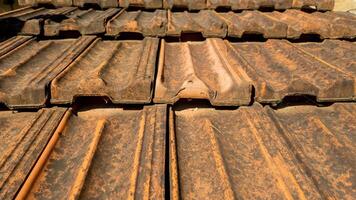 Close up of old, weathered roof tiles showing rust and decay, highlighting the need for maintenance and restoration photo
