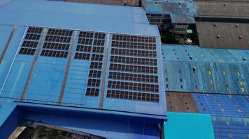 Top aerial view of solar roof system at the rooftop of factory warehouse. renewable energy of photovoltaic for reduce energy and carbon footprint. clean energy. solar panel and structure at building. video