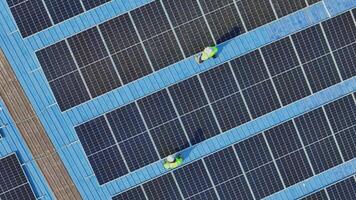 Top aerial view of engineer men inspects construction of solar cell panel or photovoltaic cell by electronic device. Industrial Renewable energy of green power. factory worker working on tower roof. video
