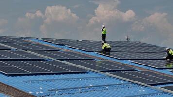Worker Technicians are working to construct solar panels system on roof. Installing solar photovoltaic panel system. Men technicians carrying photovoltaic solar modules on roof. video