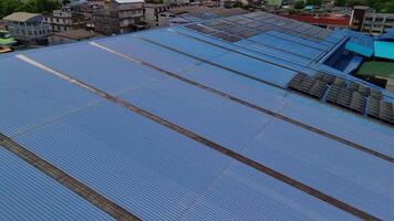 Top aerial view of solar roof system at the rooftop of factory warehouse. renewable energy of photovoltaic for reduce energy and carbon footprint. clean energy. solar panel and structure at building. video