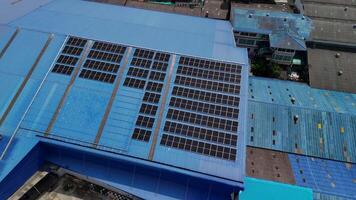 Top aerial view of solar roof system at the rooftop of factory warehouse. renewable energy of photovoltaic for reduce energy and carbon footprint. clean energy. solar panel and structure at building. video