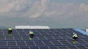 Top aerial view of engineer men inspects construction of solar cell panel or photovoltaic cell by electronic device. Industrial Renewable energy of green power. factory worker working on tower roof. video