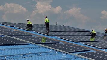 Worker Technicians are working to construct solar panels system on roof. Installing solar photovoltaic panel system. Men technicians carrying photovoltaic solar modules on roof. video