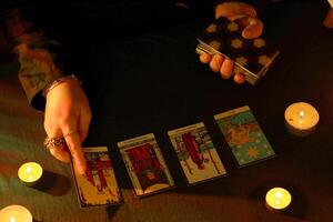 KYIV, UKRAINE - JULY 10, 2024 Tarot reader picking tarot cards. Candlelight in dark room. Tarot reader or fortune teller reading and forecasting photo