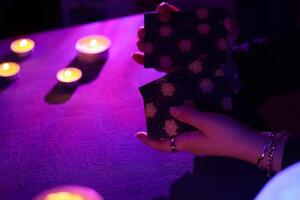 KYIV, UKRAINE - JULY 10, 2024 Tarot reader picking tarot cards. Candlelight in dark room. Tarot reader or fortune teller reading and forecasting photo