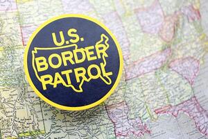 KYIV, UKRAINE - JUNE 26, 2024 U.S. Border Patrol coat of arms on paper map of United States photo