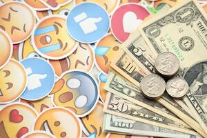 KYIV, UKRAINE - APRIL 20, 2024 USD dollars money and large set of stickers with Emoji yellow faces. The concept of smm, smo paid service for boost in social media photo
