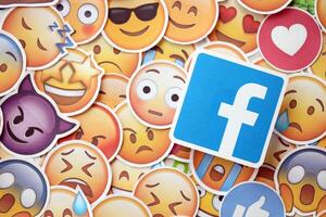 KYIV, UKRAINE - APRIL 20, 2024 Facebook logo and large set of stickers with Emoji yellow faces. Emoji is a pictogram or smiley embedded in text and used in electronic messages photo
