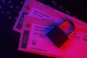 Fictional air tickets and small padlock on computer keyboard photo