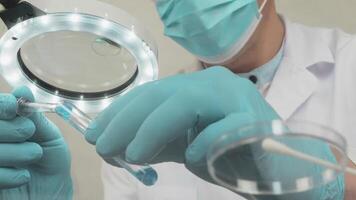 Physician works in a laboratory new vaccine research. Doctor tests blood samples. Scientist in medical mask and rubber gloves in front of a microscope Low-angle view in close-up video