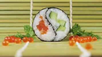 Chopsticks grab a sushi roll. Sushi roll Yin Yang on a bamboo mat in close up. Chopsticks grab sushi and lift them up. video