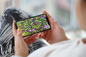 Clash of Clans mobile iOS game on iPhone 15 smartphone screen in female hands during mobile gameplay photo