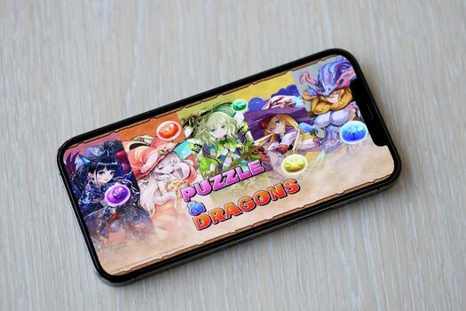 Puzzle and dragons mobile iOS game on iPhone 15 smartphone screen on wooden table during mobile gameplay photo