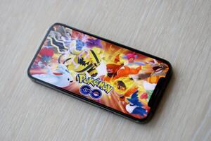Pokemon GO mobile iOS game on iPhone 15 smartphone screen on wooden table during mobile gameplay photo