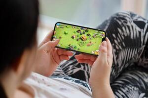 Clash of Clans mobile iOS game on iPhone 15 smartphone screen in female hands during mobile gameplay photo