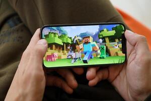 Minecraft mobile iOS game on iPhone 15 smartphone screen in male hands during mobile gameplay photo