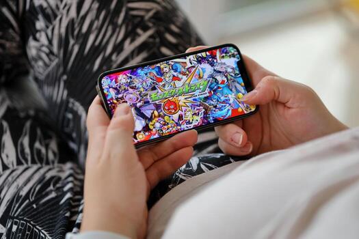 Monster Strike mobile iOS game on iPhone 15 smartphone screen in female hands during mobile gameplay photo