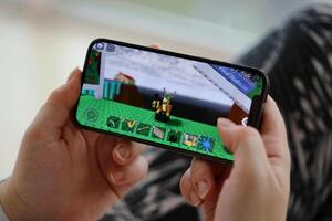 Roblox mobile iOS game on iPhone 15 smartphone screen in female hands during mobile gameplay photo