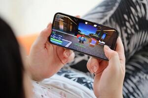 Roblox mobile iOS game on iPhone 15 smartphone screen in female hands during mobile gameplay photo