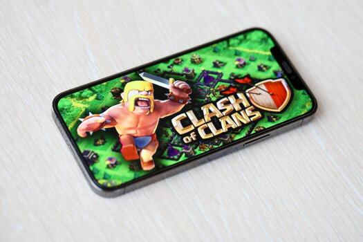 Clash of Clans mobile iOS game on iPhone 15 smartphone screen on wooden table during mobile gameplay photo