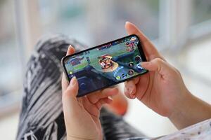 Honor of Kings mobile iOS game on iPhone 15 smartphone screen in female hands during mobile gameplay photo