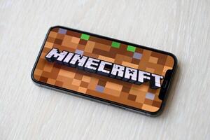 Minecraft mobile iOS game on iPhone 15 smartphone screen on wooden table during mobile gameplay photo