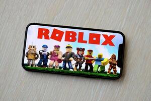 Roblox mobile iOS game on iPhone 15 smartphone screen on wooden table during mobile gameplay photo