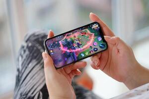 Honor of Kings mobile iOS game on iPhone 15 smartphone screen in female hands during mobile gameplay photo