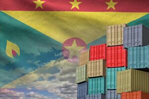 Grenada flag and big stack of shipping cargo containers in docks with sky background photo