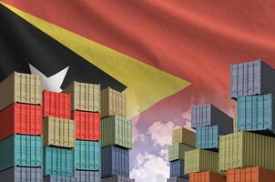 Timor Leste flag and big stack of shipping cargo containers in docks with sky background photo